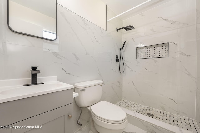 bathroom featuring a tile shower, vanity, toilet, and tile walls