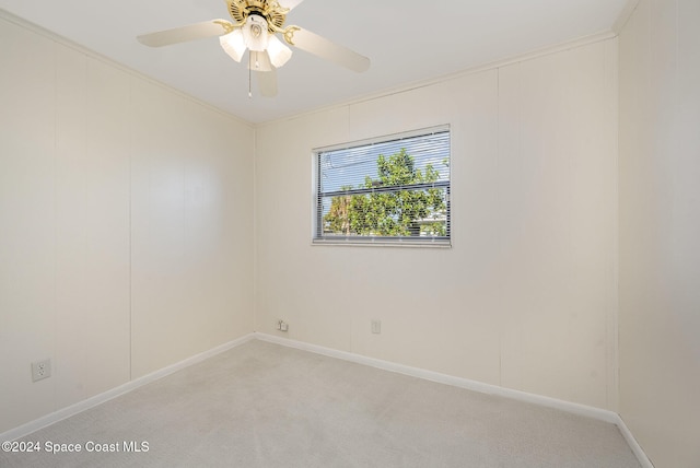 unfurnished room with ceiling fan, light colored carpet, and crown molding