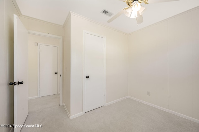 unfurnished bedroom featuring light carpet, ceiling fan, and ornamental molding