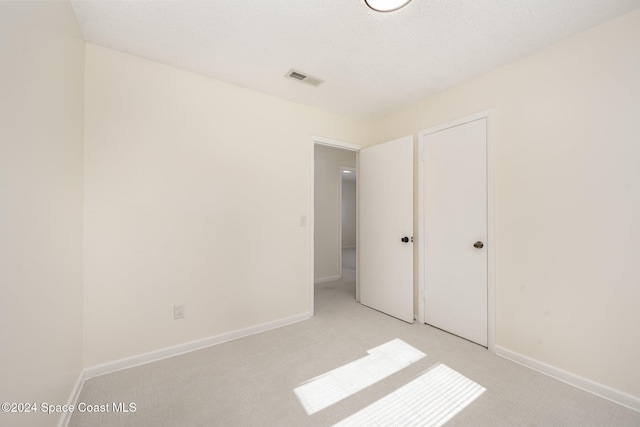 unfurnished bedroom with light carpet and a textured ceiling