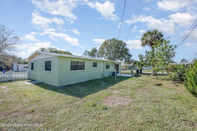 back of property featuring central air condition unit and a yard