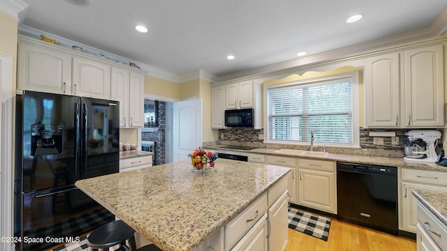 kitchen with backsplash, crown molding, sink, black appliances, and a kitchen island