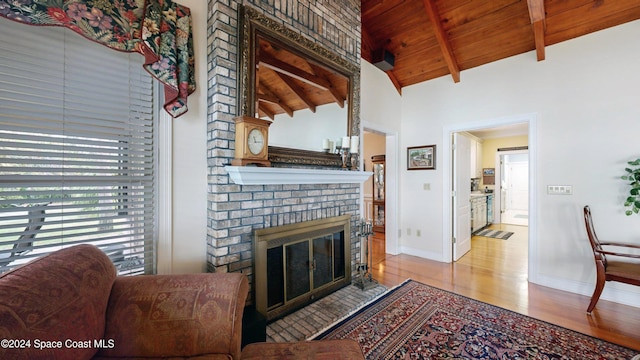 living room featuring a fireplace, vaulted ceiling with beams, light hardwood / wood-style floors, and wooden ceiling