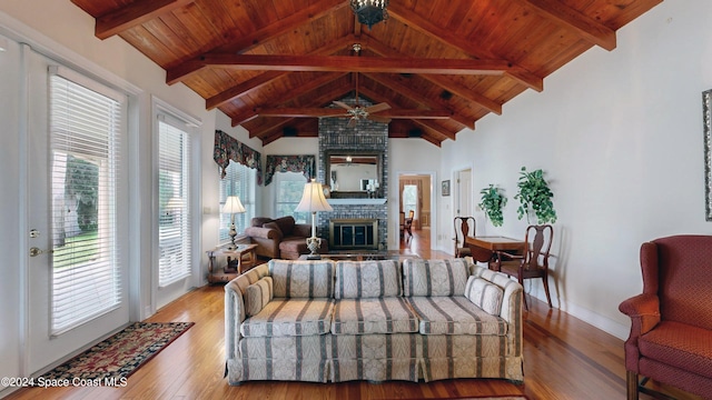 living room featuring lofted ceiling with beams, ceiling fan, a fireplace, light hardwood / wood-style floors, and wood ceiling