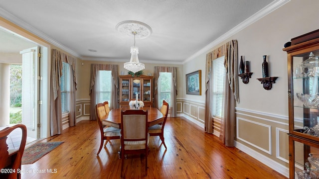 dining room featuring a notable chandelier, a healthy amount of sunlight, light wood-type flooring, and ornamental molding