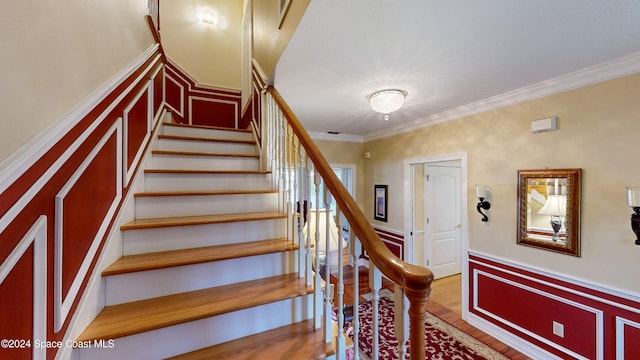 stairway with hardwood / wood-style flooring and ornamental molding