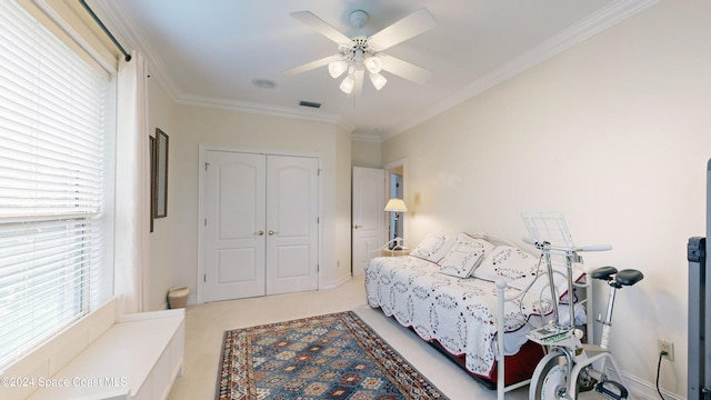 bedroom featuring ceiling fan, crown molding, light carpet, and a closet