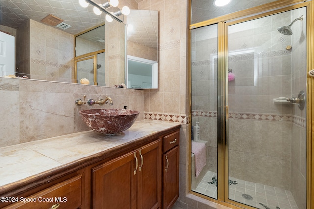 bathroom featuring vanity, a shower with door, and tile walls