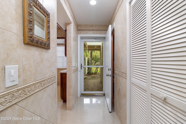 corridor featuring a textured ceiling and tile walls