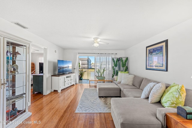 living room with a textured ceiling, light hardwood / wood-style floors, and ceiling fan