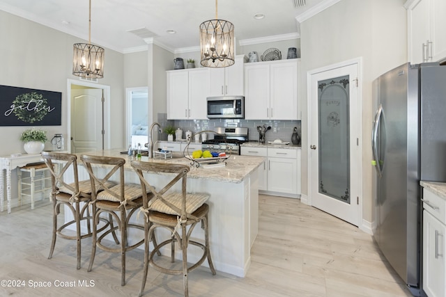 kitchen featuring white cabinets, light hardwood / wood-style flooring, stainless steel appliances, and an island with sink