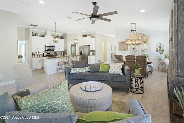 living room featuring ceiling fan with notable chandelier, light wood-type flooring, and crown molding