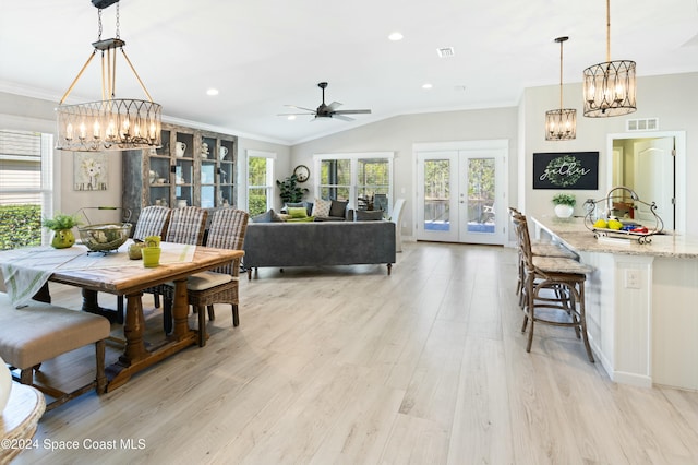 dining space with french doors, ornamental molding, vaulted ceiling, ceiling fan, and light hardwood / wood-style floors