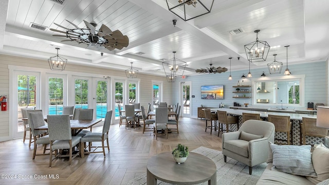 interior space with beam ceiling, light parquet floors, ceiling fan, and wooden walls