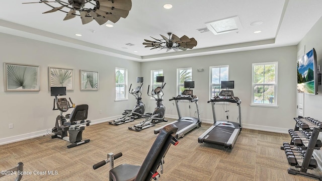 exercise room with carpet floors, a tray ceiling, and ceiling fan