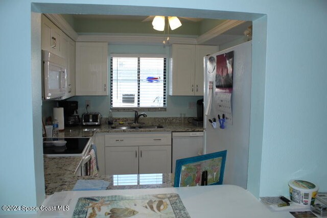 kitchen with white cabinets, white appliances, light stone counters, and sink