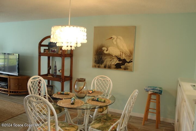 dining space with wood-type flooring and an inviting chandelier