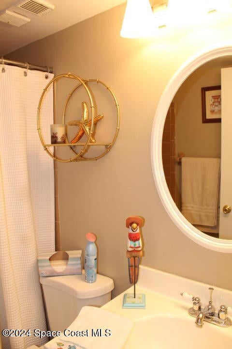 bathroom featuring curtained shower, toilet, and sink