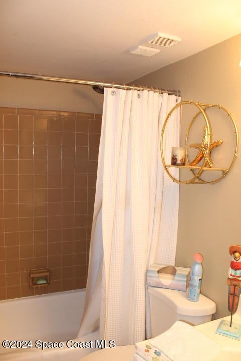 bathroom featuring toilet and shower / tub combo with curtain