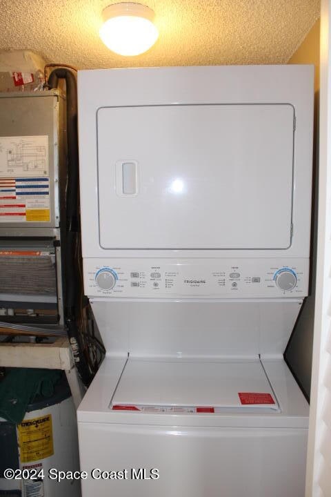 washroom with a textured ceiling and stacked washer / dryer