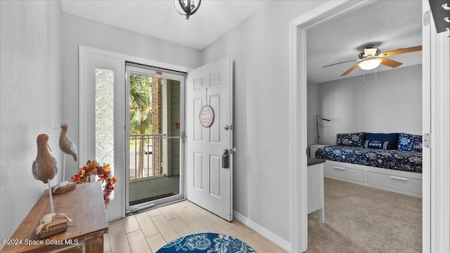 carpeted foyer with ceiling fan and a textured ceiling