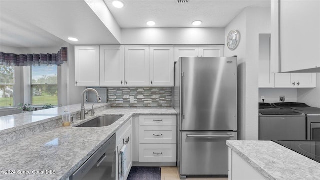 kitchen featuring white cabinets, washer and dryer, sink, and appliances with stainless steel finishes