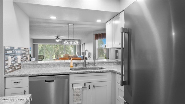 kitchen featuring white cabinetry, sink, ceiling fan, light stone counters, and appliances with stainless steel finishes