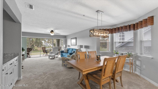 carpeted dining room featuring ceiling fan with notable chandelier and a textured ceiling