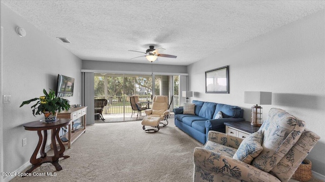 living room featuring carpet flooring, ceiling fan, and a textured ceiling