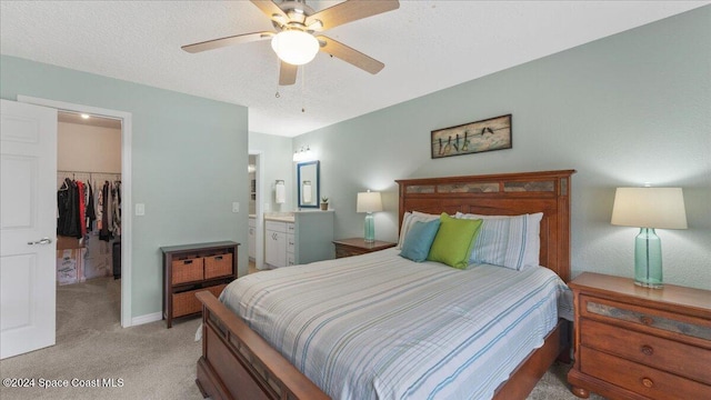 carpeted bedroom featuring connected bathroom, a spacious closet, ceiling fan, a textured ceiling, and a closet