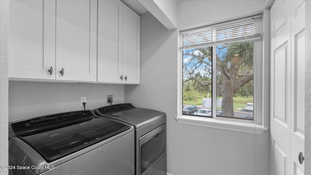 clothes washing area featuring separate washer and dryer, plenty of natural light, and cabinets