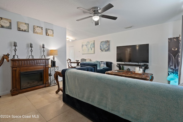 living room with ceiling fan, light tile patterned floors, and a textured ceiling