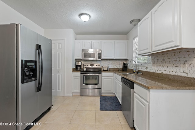 kitchen featuring white cabinets, sink, light tile patterned floors, and stainless steel appliances