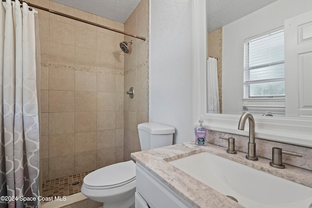 bathroom with vanity, curtained shower, toilet, and a textured ceiling