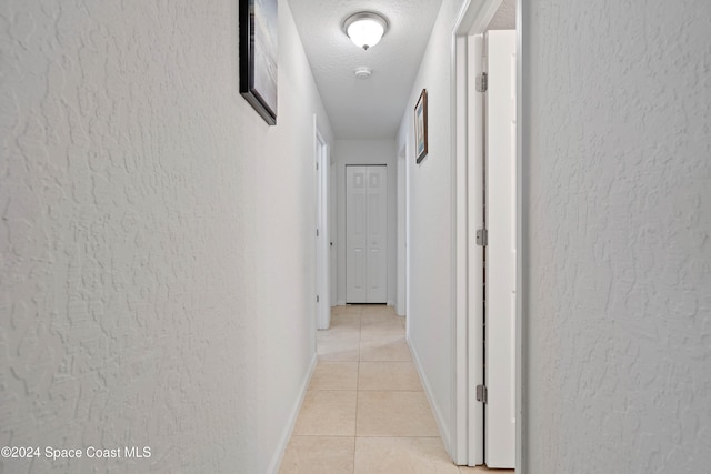 hallway with light tile patterned floors and a textured ceiling