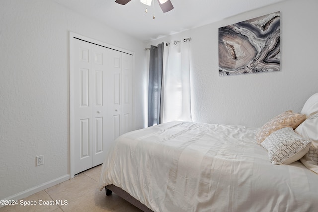 tiled bedroom featuring ceiling fan and a closet