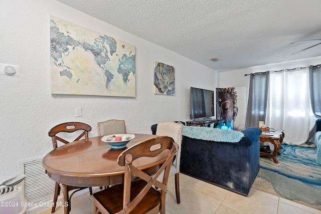 dining room featuring ceiling fan, light tile patterned floors, and a textured ceiling