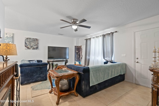 bedroom with ceiling fan, light tile patterned floors, and a textured ceiling