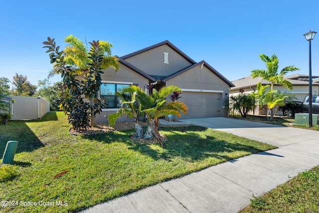 view of front of property with stucco siding, concrete driveway, a front yard, fence, and a garage