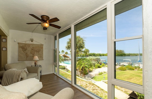 sunroom featuring a water view, plenty of natural light, and ceiling fan