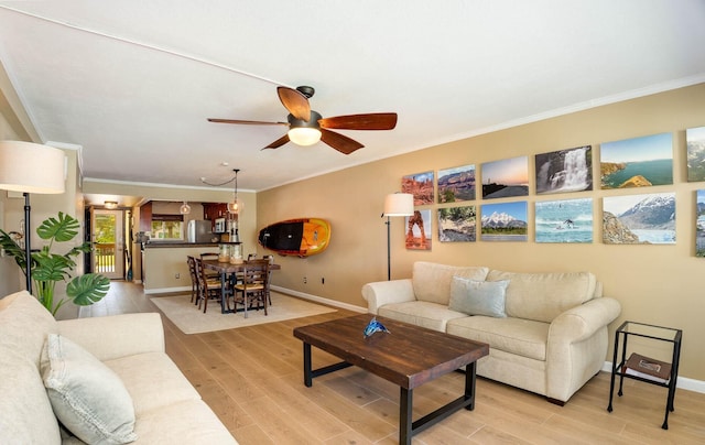 living room featuring ceiling fan, light wood-type flooring, and crown molding