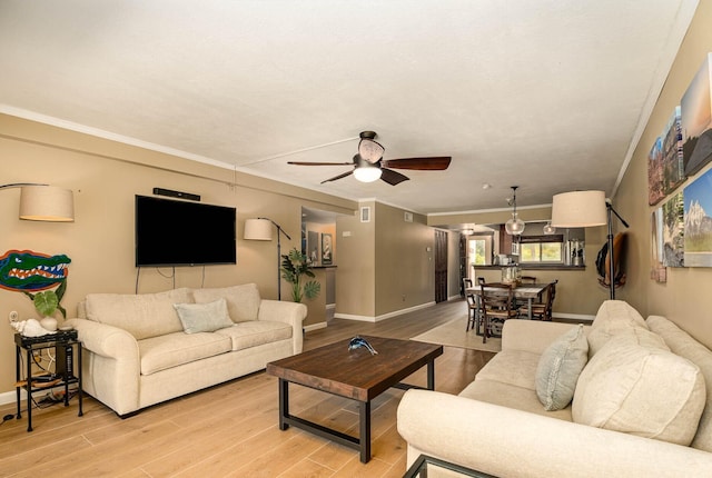 living room with ceiling fan, crown molding, and light wood-type flooring