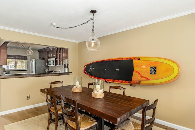 dining area with light wood-type flooring and ornamental molding