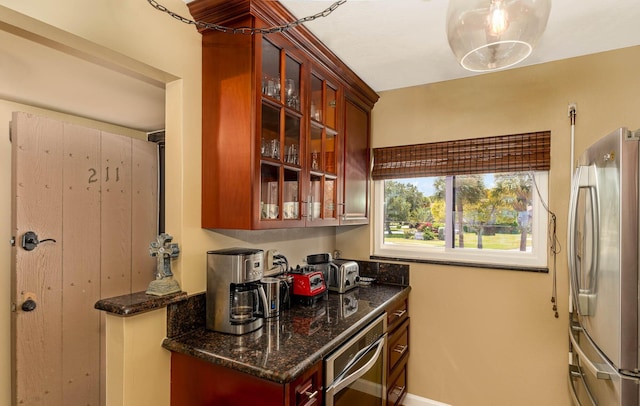 kitchen featuring decorative light fixtures, dark stone countertops, and stainless steel appliances