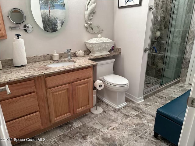 bathroom with vanity, toilet, and a shower with door