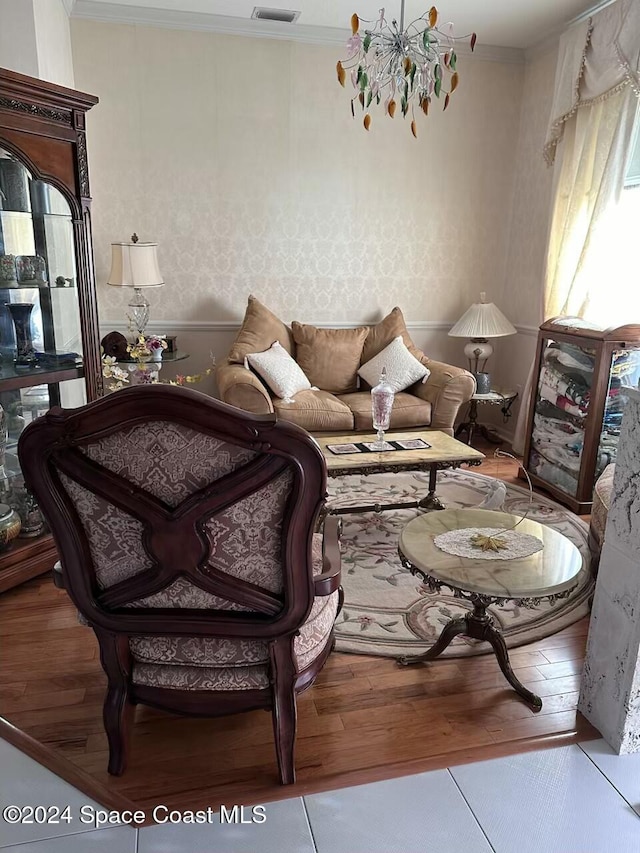 living room with an inviting chandelier, ornamental molding, and light wood-type flooring