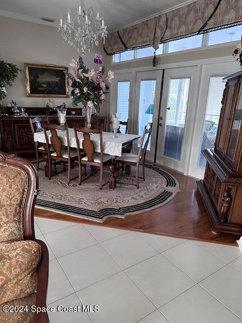 dining area featuring an inviting chandelier, light tile patterned floors, crown molding, and french doors