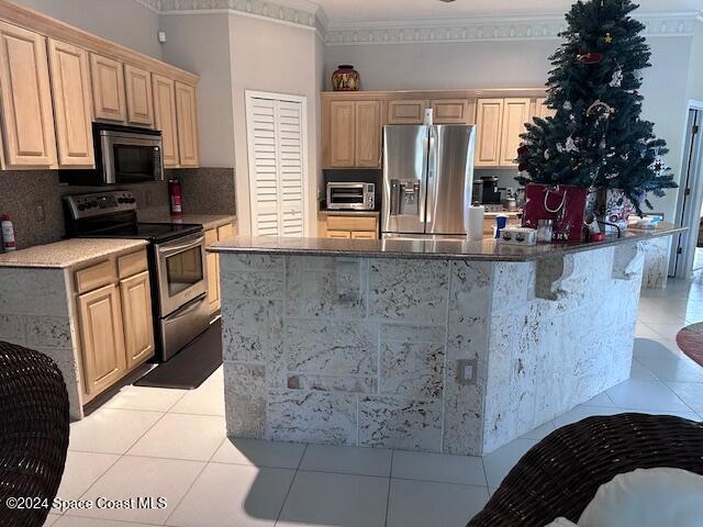 kitchen featuring light brown cabinetry, a center island with sink, and appliances with stainless steel finishes