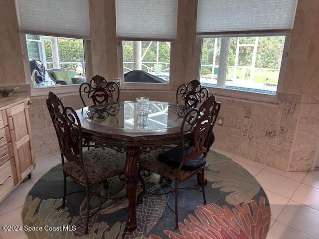 dining area featuring tile walls, light tile patterned floors, and a healthy amount of sunlight