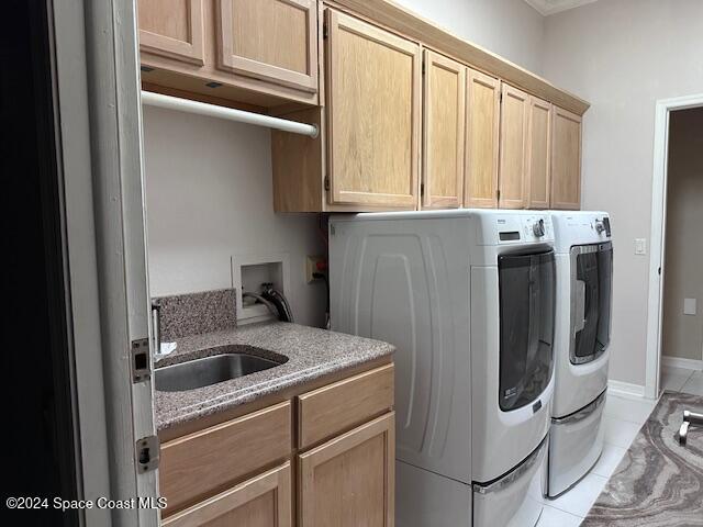 clothes washing area with light tile patterned flooring, cabinets, separate washer and dryer, and sink